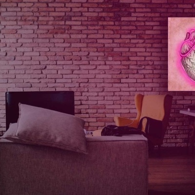 Sala de estar com parede de tijolos expostos vermelhos, sofá cinzento com almofadas e cadeira castanha