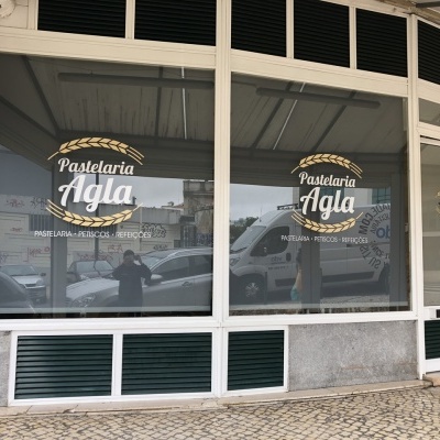 Fachada de pastelaria com janelas de vidro e inscrições em branco e amarelo