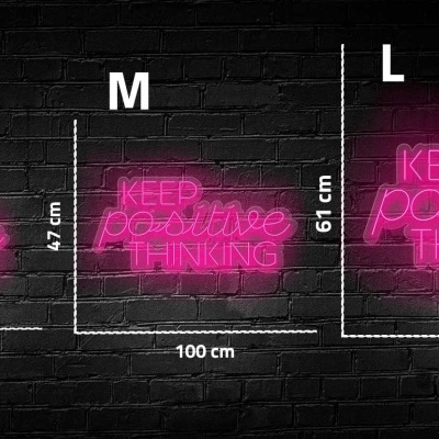 Letreiros de néon rosa com texto 'KEEP positive THINKING' em três tamanhos diferentes na parede preta de tijolo.