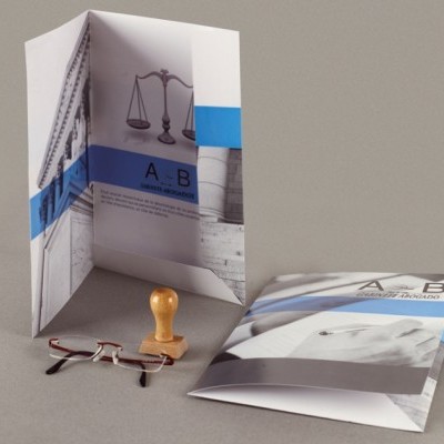 Folheto dobrado azul e branco com texto A - B e carimbo de madeira ao lado