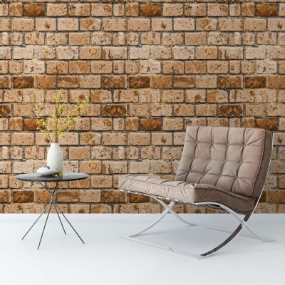 Cadeira bege acolchoada, mesa preta com vaso e parede de tijolos