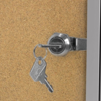 Chave de metal na fechadura prateada numa porta castanha clara com estrutura branca