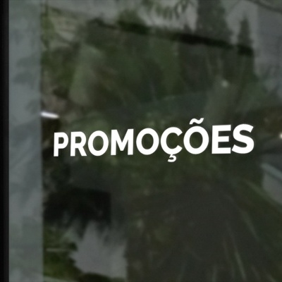 Vidro com texto branco PROMOÇÕES e reflexo de planta e escada
