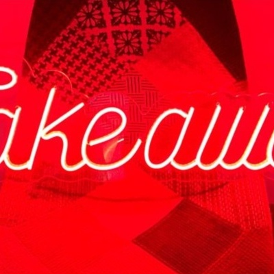 Palavra 'Takeaway' iluminada em branco sobre cadeira xadrez vermelha e preta