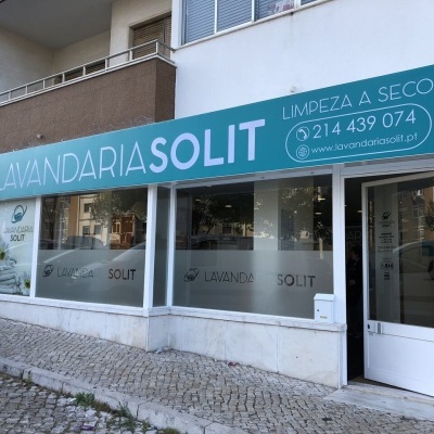 Fachada de lavandaria com letreiro azul e branco e vidro translúcido