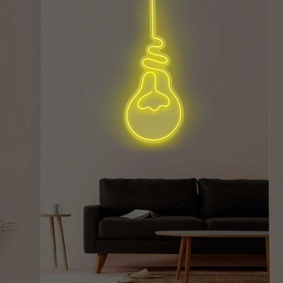 Parede cinzenta com luz de néon amarela em forma de lâmpada e sofá escuro em sala minimalista