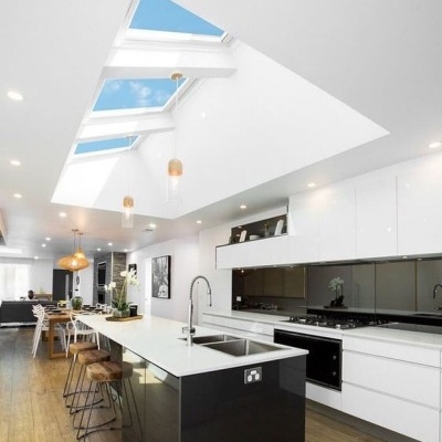 Cozinha moderna branca com ilha preta e claraboias no teto