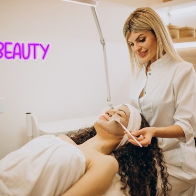 Tratamento facial com esteticista num ambiente de estética com luz neon 'BEAUTY'
