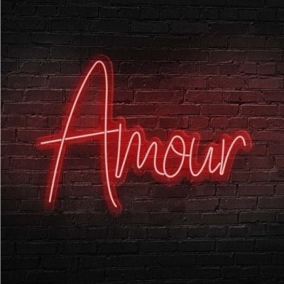 Letreiro de neon vermelho com a palavra 'Amour' numa parede de tijolos preta