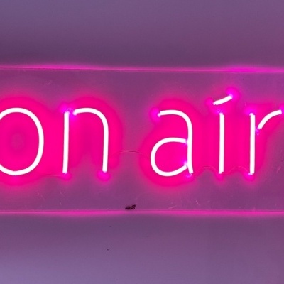 Luz de néon rosa com texto '(on air)'