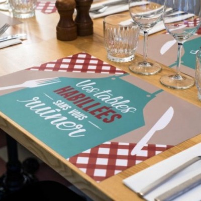 Individuais para mesa coloridos com padrão xadrez e texto em português numa mesa de restaurante