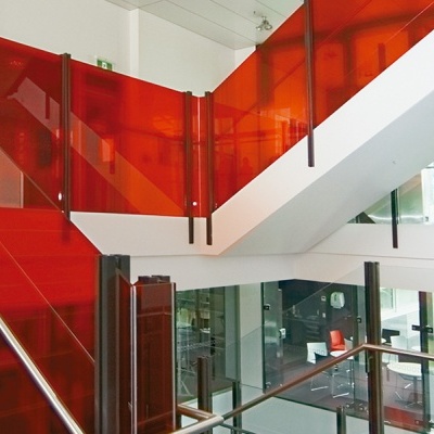 Escada interior com painéis de vidro vermelho e corrimão de metal