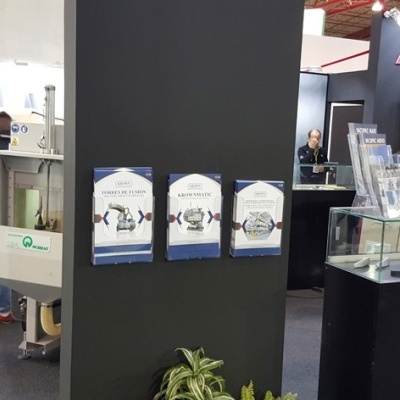 Stand de feira com parede preta, folhetos de relógios e expositores em vidro