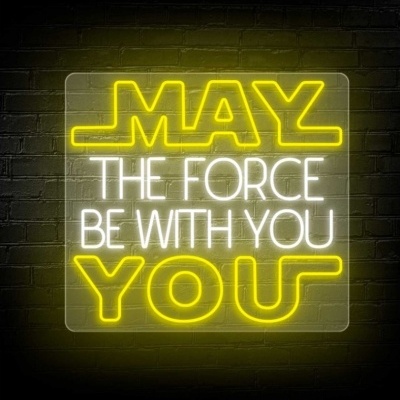 Letreiro de néon amarelo e branco com a frase 'MAY THE FORCE BE WITH YOU' numa parede de tijolos.