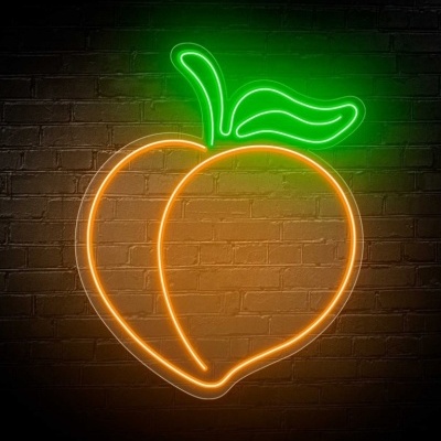 Luz de neon em forma de pêssego em parede de tijolos
