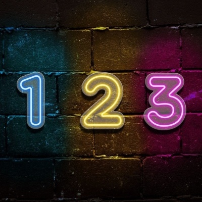 Números 1, 2 e 3 em néon iluminados em parede de tijolos escura