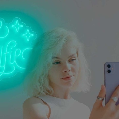 Mulher tirando selfie com placa neon azul 'Take a Selfie'