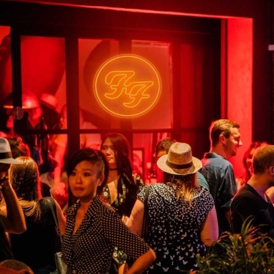 Grupo de pessoas numa sala iluminada a vermelho com um logótipo circular iluminado e texto pintado na parede.