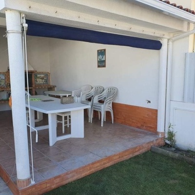 Área exterior coberta com mesa branca, cadeiras e banco de madeira com azulejos