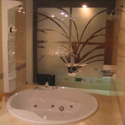 Banheira branca de hidromassagem embutida em pedra clara com vidro fosco decorado