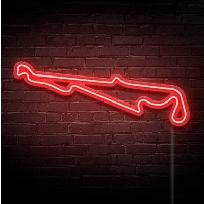 Letreiro néon vermelho em forma de pista de corrida numa parede de tijolos