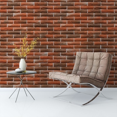 Cadeira bege estofada com mesa preta e vaso com flores amarelas em frente a parede de tijolo vermelho.