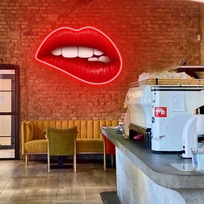 Interior de café com parede de tijolos e luminária de néon em forma de boca vermelha