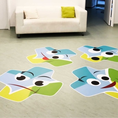 Tapetes em forma de peixes coloridos no chão de uma sala com sofá branco