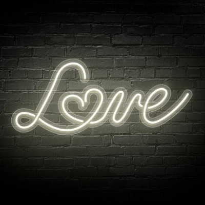 Letreiro luminoso em néon branco com a palavra 'Love' e um coração, numa parede de tijolos preta