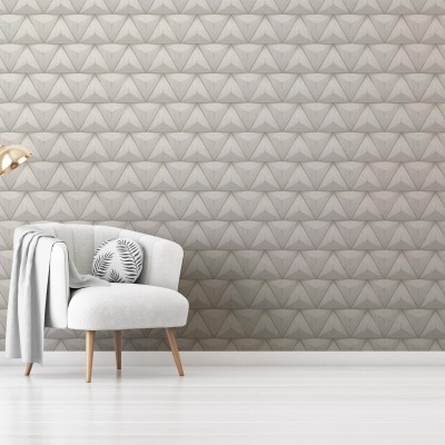 Poltrona cinzenta clara com almofada, candeeiro dourado e parede com padrão geométrico cinzento