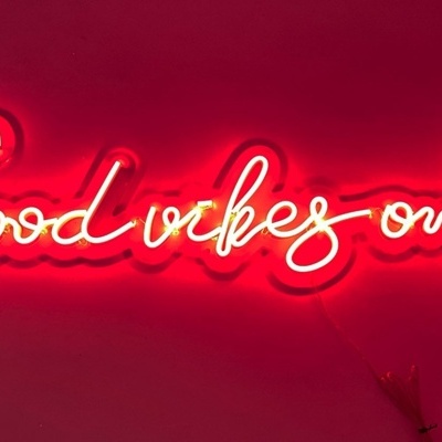 Letreiro de néon com texto 'Good vibes only' em fundo vermelho