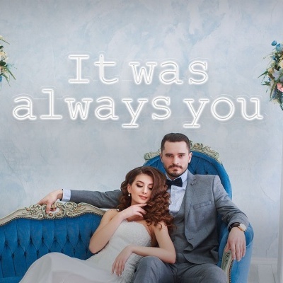 Casal elegante num sofá azul vintage com arranjos florais e texto no fundo