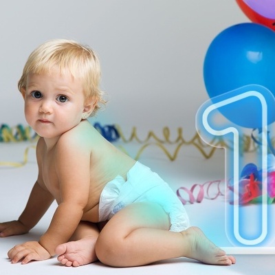 Bebé com fralda azul, balões coloridos e número 1 em fundo branco