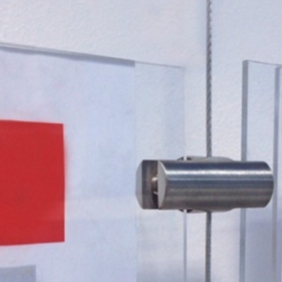 Fecho metálico fixado em vidro transparente com fundo branco e quadrado vermelho