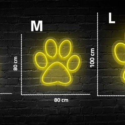 Luzes de néon amarelas em forma de pata animal em três tamanhos contra parede preta