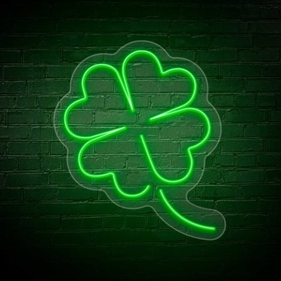 Luz neon verde em forma de trevo de quatro folhas num fundo de parede de tijolos escuros