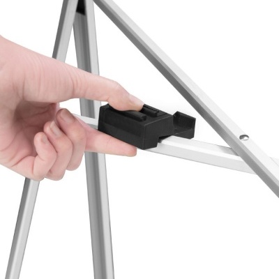 Mão segurando peça plástica preta em tripé metálico prateado.