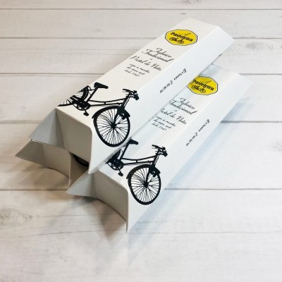 Duas caixas brancas para bicicleta com ilustração de bicicleta preta e texto em inglês numa mesa branca