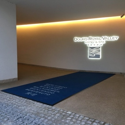 Tapete azul com texto branco numa entrada iluminada com placa DOuRO ROYAL VALLEY HOTEL + SPA