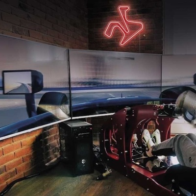 Simulador de corrida com três ecrãs e banco em ambiente interior