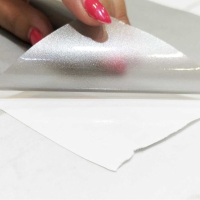 Mão a descolar folha plástica transparente de superfície branca