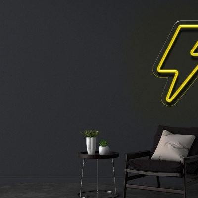 Sala com parede cinzenta escura, poltrona preta, mesa pequena e sinal de raio amarelo em néon