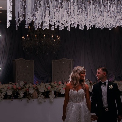 Noivos com decoração floral e letreiro de lua iluminado com texto 'TO THE MOON & BACK'.