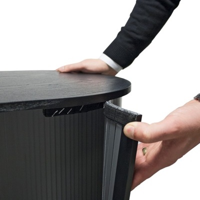 Móvel metálico preto com acabamento em madeira escura e porta nervurada sendo aberta por mãos