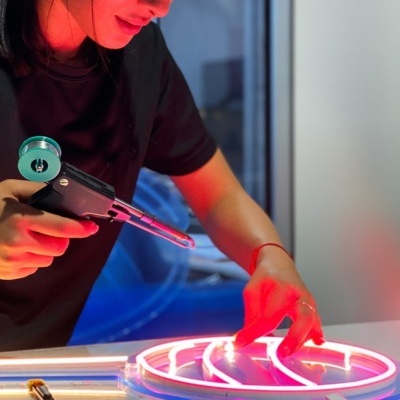 Mulher a aplicar luzes LED rosa com pistola de calor em objeto circular