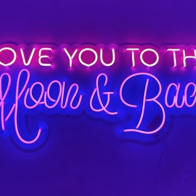 Neon sign with the phrase LOVE YOU TO THE Moon & Back in pink and purple