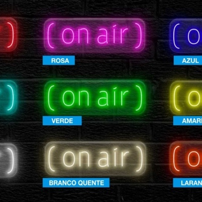 Letreiros luminosos com a frase 'on air' em diversas cores neon sobre fundo preto de parede de tijolos.