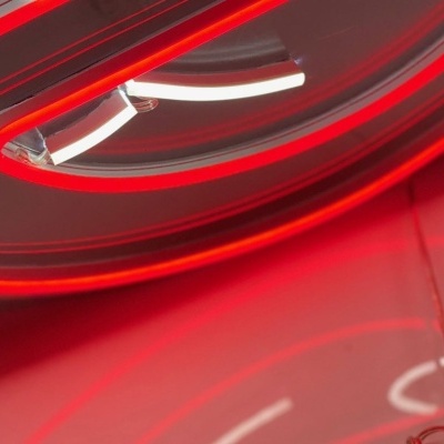 Detalhe de letreiro de néon vermelho num fundo rosa