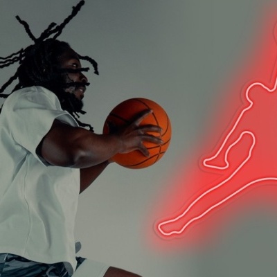 Homem a jogar basquetebol com ténis brancos e logo vermelho Jumpman no fundo.