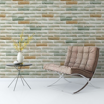 Poltrona castanha com mesa de apoio preta e vaso branco com flores contra parede de tijolos verdes e bege